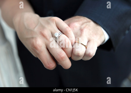 Bride and Groom Holding Hands and Showing Wedding Rings, Close-Up Stock Photo