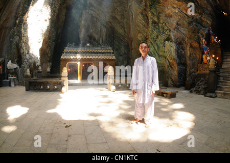 Marble Mountains, Priest standing in ray of light illuminating Huyen Khong cave. Danang, Vietnam Stock Photo