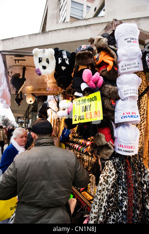 Oxford Street London West End stall with novelty hats scarves watches chains etc vendor serves grey haired woman lady Stock Photo