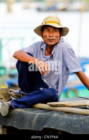 Man Smoking Cigarette on the Roof of his Boat, Hoi An, Vietnam Stock Photo
