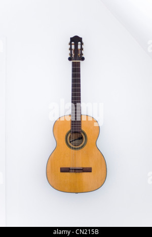 Classical Guitar with Missing String Hanging on White Wall Stock Photo