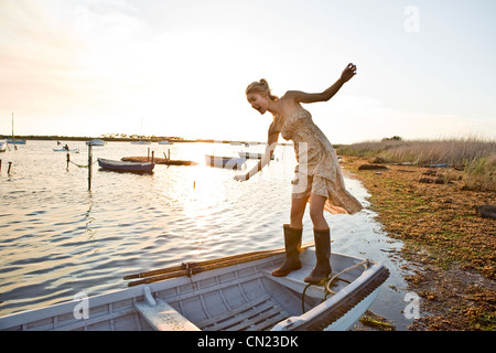 Smiling Young Woman in Gum Boots Balancing on Boat Stock Photo