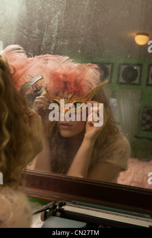 Teenage girl wearing masquerade mask in front of mirror Stock Photo