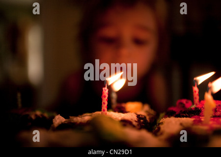 3 year old boy blowing out candles on birthday cake Stock Photo