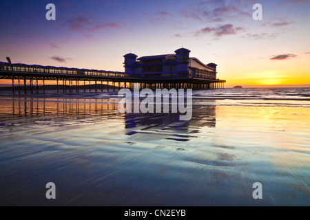 Sunset over the Grand Pier at Weston-Super-Mare, Somerset, England, UK reflected in the wet sand of the beach at high tide.