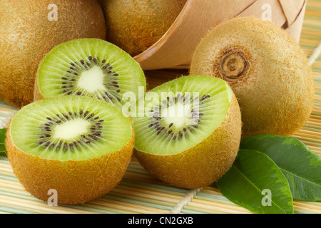 kiwi sliced and whole fruits, basket on table Stock Photo