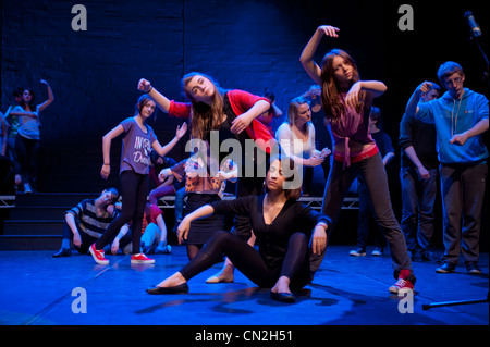 A group of boys and girls, teenagers singing and dancing in a amateur musical theatre performance production in a theatre. UK Stock Photo