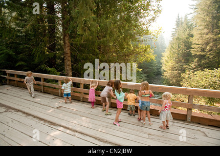 Group of children standing on wooden bridge in forest