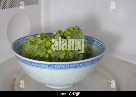 Frozen peas defrosting in microwave Stock Photo