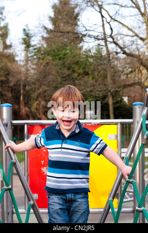 Portrait of a two year old boy laughing as he plays on a climbing frame Stock Photo