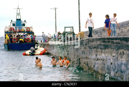 Aran Islands- Boys swim by the harbour wall on INISHEER as the Doolin Ferry prepares to depart. Stock Photo