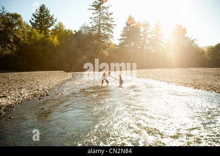 Mother with two children playing in river Stock Photo