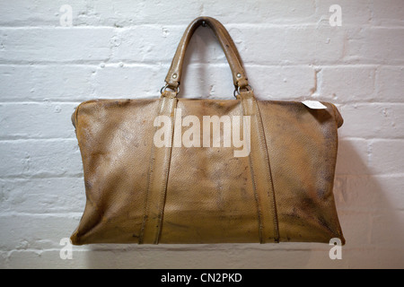 Leather holdall hanging on brick wall Stock Photo