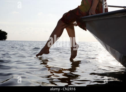 Senior woman sitting on edge of motorboat with feet in water Stock Photo