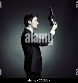 Surreal portrait of a stylish man in an elegant suit and shoes in hand Stock Photo