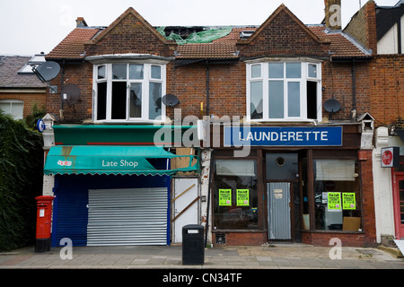 Abandoned and boarded up / closed shut-up derelict shops (GPO Post Office and a laundry / launderette) in Twickenham. London. UK Stock Photo