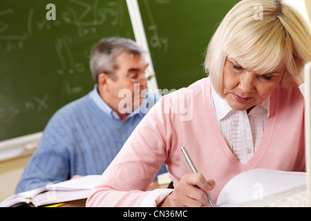 Pensive seniors trying to cope with a hard task in school, tilt up Stock Photo