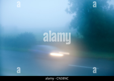Car driving in fog down country road Stock Photo