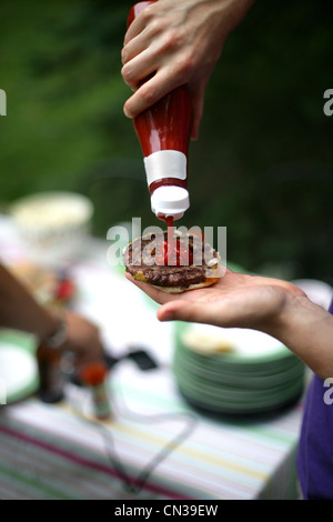 Hand squeezing tomato ketchup bottle Stock Photo - Alamy