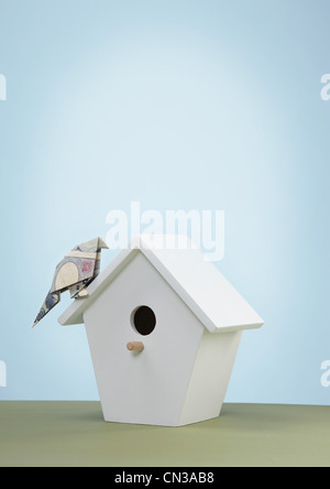 Origami yen banknote imitating bird on bird box Stock Photo