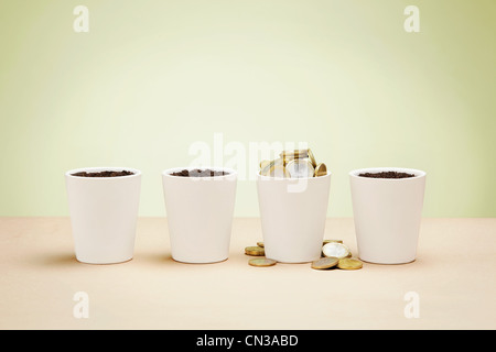 Four plant pots, one full of euro coins Stock Photo