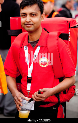 Young Asian man selling beer, carrying a dispenser on his back, London, England, UK Stock Photo