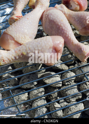 Raw uncooked chicken drumsticks on a barbecue. Stock Photo