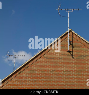 A television aerial on a house roof, set against a blue sky. Stock Photo