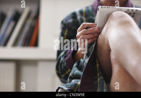 Senior man in robe relaxing with newspaper Stock Photo