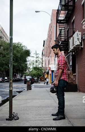 Young man looking at broken bike on street Stock Photo