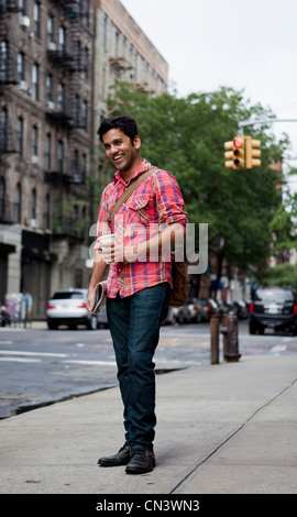 Young man walking along city street, smiling Stock Photo