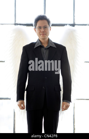 Man Wearing a Business Suit with Wings Standing in Front of a Large Bright Window, Montreal, Quebec Stock Photo