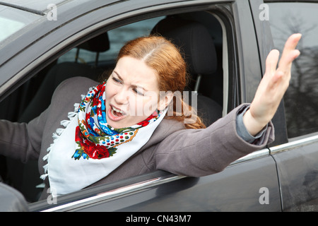 Pretty young Caucasian woman shaking hers hand and screaming sitting in car Stock Photo
