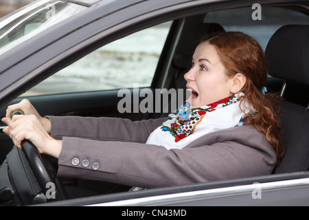 Pretty young Caucasian woman stopping the car and screaming. Looking forward Stock Photo