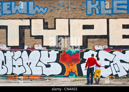 United Kingdom, London, Hackney, Shoreditch, couple in front of a graffiti wall Stock Photo