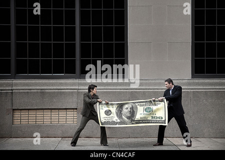 Man and woman fighting over large $100 bill Stock Photo