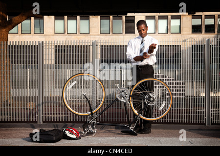 Young businessman rolling sleeves to fix bicycle Stock Photo