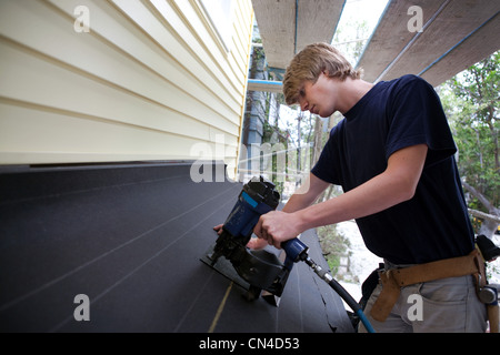 Teenage boy using nail gun on construction site Stock Photo