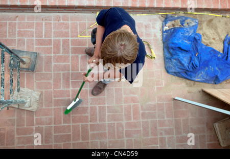 Teenage boy sweepingn on construction site Stock Photo