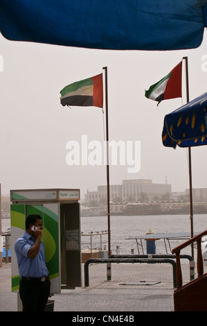 National flags of UAE and a man on  a mobile phone, Dubai Creek, United Arab Emirates Stock Photo