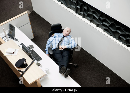 Security guard sleeping at desk Stock Photo