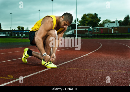 Sprinter tying shoelace on race track