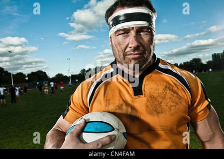 Rugby player holding ball on pitch, portrait Stock Photo