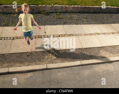 Young girl skipping on sidewalk Stock Photo