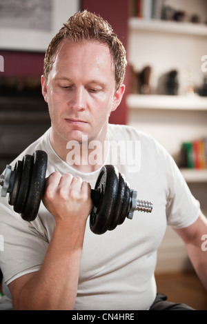 Mid adult man lifting dumb bell in home Stock Photo