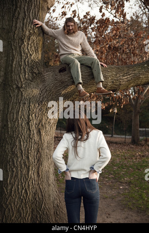 Girl looking up at boy in tree Stock Photo