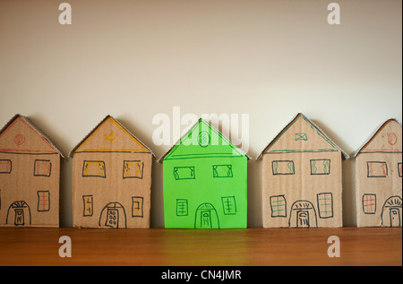 One green cardboard house amongst others Stock Photo