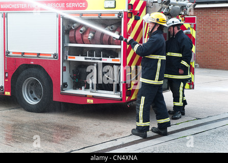 Firefighters spraying a fire hose from a tuck Stock Photo