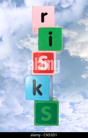 assorted childrens toy letter building blocks against a cloud background that spell risks with clipping path Stock Photo