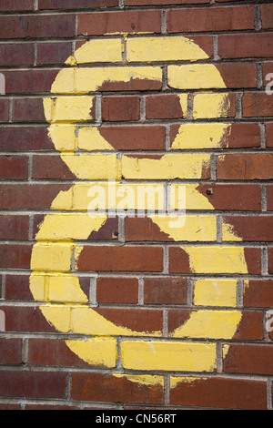 A handmade yellow number 8 painted on a red brick wall. Stock Photo